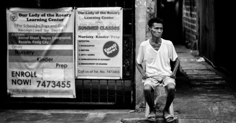 Old man, sitting intently by the street.