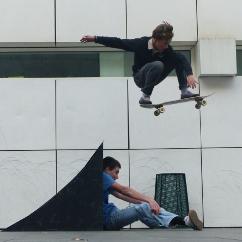 Boy jumping above his friend on a skateboard