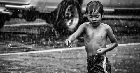 Holding onto his loose shorts, while bathing in the rain.