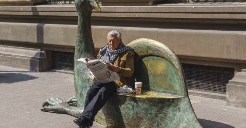 Reading a newspaper seating a bench